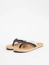 Ojotas Tommy Hilfiger con plantilla de corcho natural, base color beige y tiras acolchadas con el logo de la marca en blanco, marrón y negro.