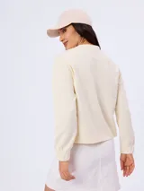 Buzo de piqué color beige, de manga larga, cuello redondo y diseño liso.