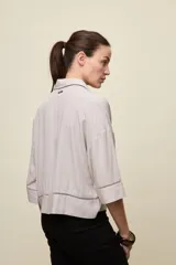 Camisa de calce relajado color celeste, con mangas 3/4, cuello clásico y cierre frontal con botones. Presenta detalles calados en el frente y en las mangas que aportan un acabado delicado al diseño.