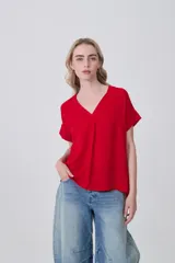 Blusa de poliéster color rojo, con cuello en V, mangas cortas y diseño holgado con pinza central.