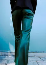 Pantalón flare de tiro bajo con efecto cuero, color verde oscuro, de corte entallado y diseño largo con cierre de gancho y cremallera.