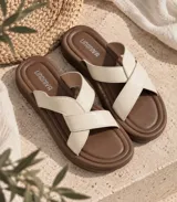 Sandalias planas con base marrón y tiras cruzadas en color beige.