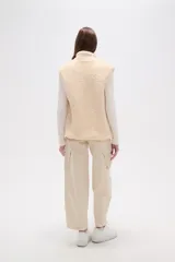 Chaleco sin mangas de textura peluche (teddy) color crema, con cuello alto y cierre frontal de cremallera.