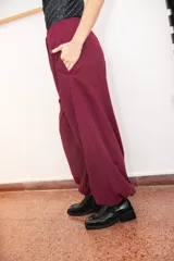 Pantalón tipo babucha de silueta relajada, color bordo, con cintura elástica ajustable mediante cordón y elásticos en los tobillos que generan un efecto abuchonado. Confeccionado en tela suave con acabado tipo piel de durazno.