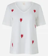 Remera de mangas cortas color crema, confeccionada en tejido flamé, con escote en pico y bordado delantero de langostas rojas.