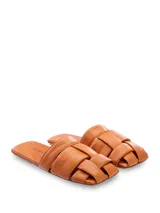 Sandalias mule chatas de cuero color suela, con capellada trenzada y plantilla forrada. Modelo de punta cuadrada.