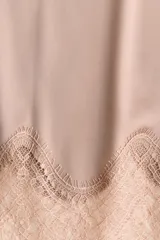 Falda midi color rosado, confeccionada en tejido fluido de satén con cremallera lateral oculta. Presenta un bajo festoneado de encaje y abertura pronunciada en un lateral.