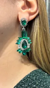 Aros colgantes de diseño elaborado con cristales verdes en forma de gota y marquise, rodeados por pequeños cristales transparentes engarzados en metal plateado.