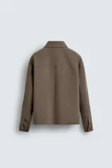 Sobrecamisa negra de corte boxy fit en tejido compacto, con cuello solapa, manga larga con puño abotonado, bolsillos frontales aplicados y cierre frontal de botonadura.