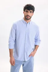 Camisa de lino de manga larga con diseño a rayas en color azul claro y blanco, cuello abotonado y cierre frontal de botones.