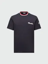 Camiseta de manga corta color blanco hueso con cuello redondo de punto acanalado a rayas en tonos rojo, azul marino y blanco. Presenta un pequeño logo bordado en azul marino en el pecho.