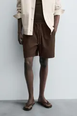 Bermuda de algodón color beige claro, de corte regular fit, con cintura elástica ajustable mediante cordón. Presenta bolsillos laterales y un bolsillo trasero de vivo.