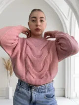 Sweater tejido de punto grueso color rosa con diseño de trenzas en el frente y mangas abullonadas.