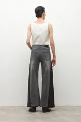 Jean wide leg bicolor en tonos de gris oscuro, con paneles laterales más oscuros y ruedo deshilachado.