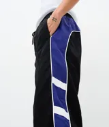 Pantalón deportivo de corte recto confeccionado en microfibra de poliamida, color negro con paneles laterales en color violeta y detalles en blanco. Cuenta con cintura elástica con cordón ajustable.