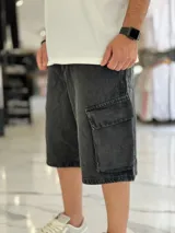 Bermuda de jean estilo cargo con bolsillos laterales con solapa, corte super baggy y lavado efecto desgastado.