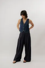Chaleco de denim azul con cuello en V, cierre frontal con botones metálicos y pespuntes en contraste.