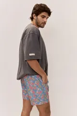 Short de baño celeste con estampa tropical de flores, cintura con cordón ajustable y detalle de etiqueta textil en el lateral.