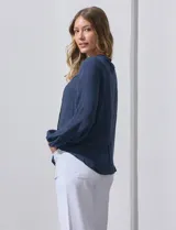 Blusa azul marino de Zac & Rachel con cuello a la base, abertura central con botones y detalle de broderie en el frente. Tiene mangas largas con terminación elastizada.