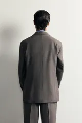 Blazer regular fit de Zara, confeccionada en tejido gris con mezcla de lana, con solapas de muesca, cierre de botonadura frontal y bolsillos con solapa en la cadera.