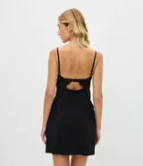 Camisón corto de color negro, confeccionado en tul con detalles de encaje floral en el busto y laterales. Presenta tirantes finos regulables, escote en V con detalle metálico central y un corte fluido con abertura lateral.