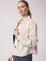 Chaqueta de lino color beige, de corte recto y holgado, con mangas largas, cuello camisero y cierre frontal de botones carey. Cuenta con bolsillos en el pecho y puños abotonados.