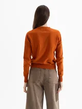 Sweater de tejido de punto color naranja, con cuello redondo, mangas largas y puños acanalados. Presenta una textura suave y un diseño clásico de calce estructurado.
