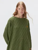 Sweater de punto color verde oliva con diseño de rombos en relieve, cuello redondo y calce holgado. Presenta aberturas laterales en el ruedo, puños con detalle de franjas en contraste y logo bordado en el pecho.