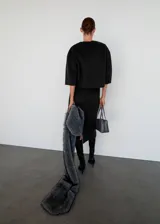 Top de corte recto confeccionado en tejido mezcla de lana, con cuello redondo y mangas tres cuartos. Presenta un diseño minimalista con cierre de cremallera en la parte posterior.