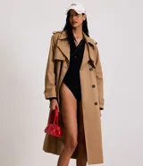 Trench coat largo de Marfinno, confeccionado en gabardina de poliéster. Presenta cuello con solapas, aletas en los hombros, cierre frontal con botones y cinta para lazo en la cintura.
