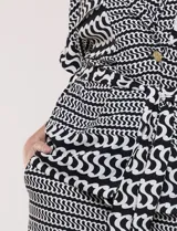 Conjunto de dos piezas de calce fluido y relajado con estampado geométrico en blanco y negro. Incluye una chaqueta con escote en V, solapa, diseño cruzado con lazo y bolsillos con solapa en el pecho, y un pantalón de tiro alto y corte wide leg.