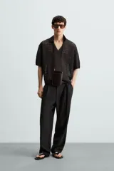 Polo de manga corta confeccionado en tejido de punto calado con estructura abierta. Presenta un diseño de corte relajado, cuello solapa con abertura frontal en pico y terminaciones acanaladas en puños y bajo.