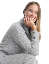 Buzo de tejido suave con cuello volcado ajustable mediante cordones con punteras metálicas. Presenta mangas largas con puños decorados con botones metálicos, hombros caídos y ruedo redondeado con aberturas laterales.