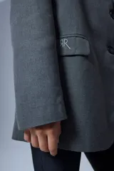 Saco sastrero oversize gris con bolsillos delanteros, forro de tafeta a tono, bordado en la tapa del bolsillo y etiqueta RENÉE tejida.