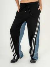 Pantalón de jean azul con corte jogger, cintura elastizada con cordón de ajuste y detalle de tres rayas blancas verticales en los laterales.