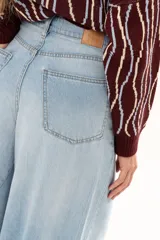 Jean de tiro alto con diseño de pierna extra ancha y caída fluida. Cuenta con bolsillos delanteros y traseros, cierre frontal con cremallera y botón metálico.