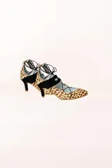 Zapatos de tacón con estampado animal print, detalles en ante negro, cordones finos y borlas decorativas.