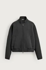 Campera relaxed fit confeccionada en tejido técnico compacto con elasticidad, de color gris oscuro. Cuenta con cuello subido, cierre frontal con cremallera, bolsillos de vivo en la cadera, manga larga y bajo con rib elástico.
