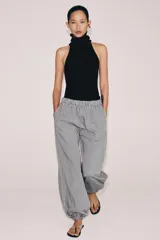 Pantalón de tiro medio con pierna ancha y cintura elástica, confeccionado en mezcla de viscosa con diseño de rayas verticales en tonos mostaza y marrón.