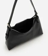 Cartera tipo baguette de tamaño pequeño, confeccionada en poliuretano con acabado brillante. Presenta un diseño minimalista con cierre de cremallera metálica superior, herrajes en níquel y correa de hombro ajustable con hebilla.