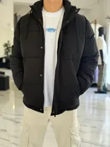 Campera puffer impermeable color beige con capucha desmontable con cordones negros, cierre frontal con cremallera y solapa con botones a presión.