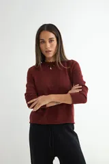 Sweater de punto color bordó, con cuello redondo con detalle de terminación ondulada y mangas largas.
