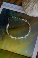 Collar corto con cuentas de piedra, conchas y cristal en tonos blanco, beige, marrón y celeste.