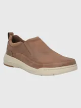 Zapato tipo slip-on Hush Puppies modelo Hunt, confeccionado en cuero color marrón con suela de EVA y goma en tono beige. Presenta elásticos laterales para facilitar el calce y un diseño de estilo casual.