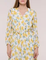 Vestido maxi de gasa con estampado floral en tonos amarillos y verdes sobre base blanca, escote en V cruzado, mangas largas y cintura elastizada con lazo.