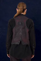 Chaleco de denim con proceso de encuerado, de corte recto y escote en V. Presenta cierre frontal con botones y bolsillos delanteros con solapa.