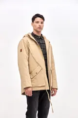 Campera tipo parka de gabardina color beige, con capucha ajustable, cierre frontal y bolsillos laterales con solapa. Presenta un diseño clásico con interior capitoneado.
