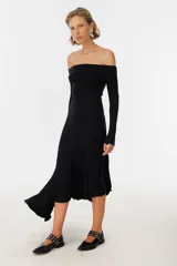 Vestido midi negro con escote off-shoulder, mangas largas y falda con volados asimétricos.