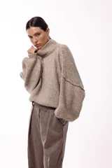 Sweater de punto grueso con cuello alto, diseño de hombros caídos y mangas amplias con puños acanalados.
