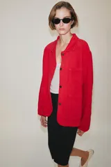Chaqueta oversize de corte recto en color rojo, con cuello solapa, manga larga y bolsillos de parche delanteros. Cuenta con cierre frontal de botones metálicos y pespuntes a contraste.